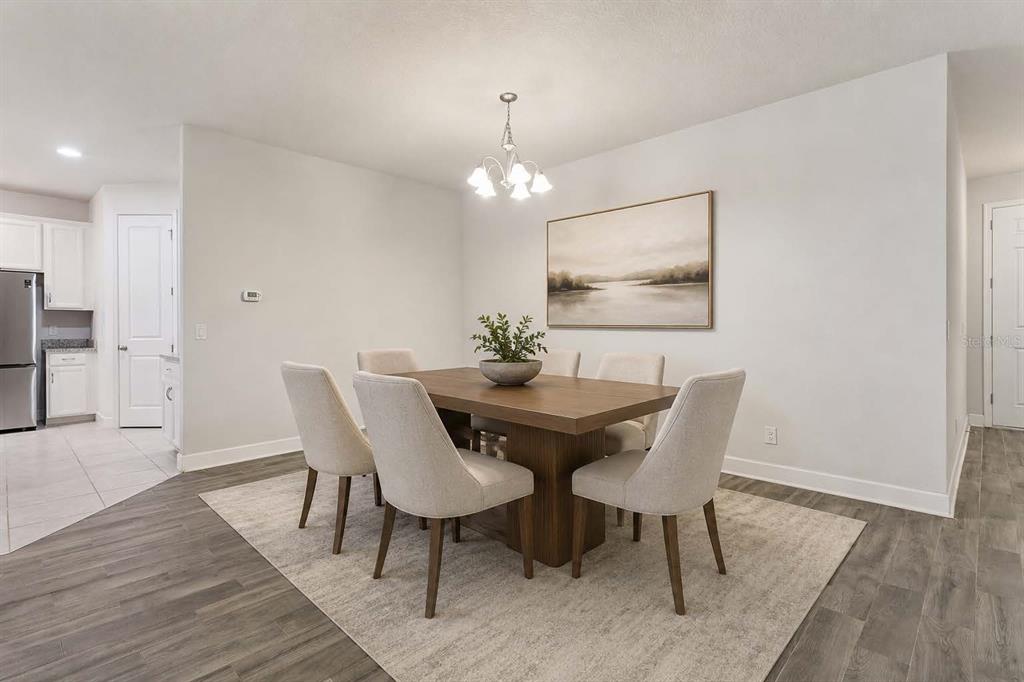 A dining room features a wooden table, six upholstered chairs, and a landscape wall art piece — 523 BELLISSIMO PLACE, HOWEY IN THE HILLS, FL