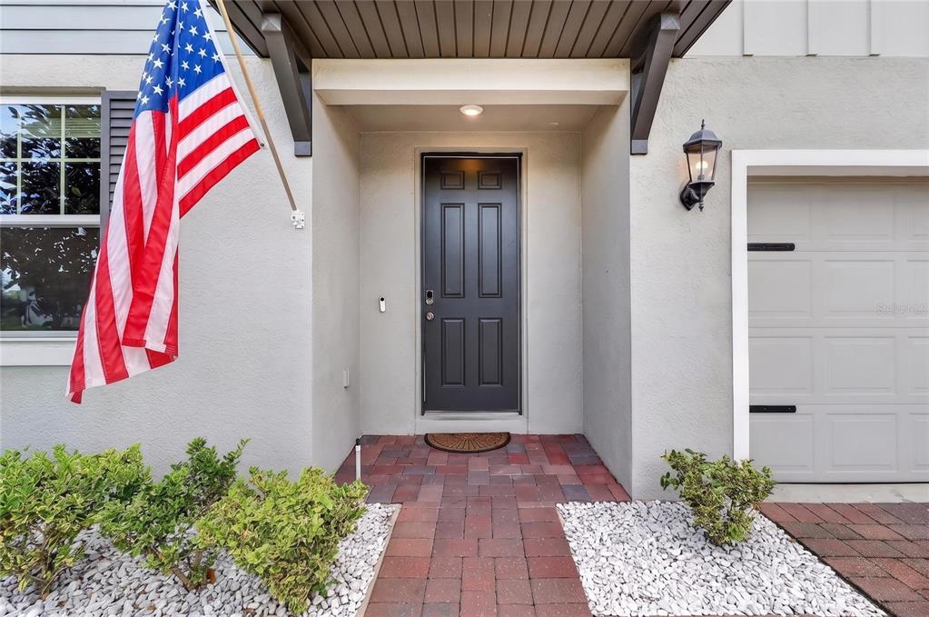 The front entrance features a dark door, a brick walkway, and an American flag — 3310 WEITZEL DRIVE, HAINES CITY, FL