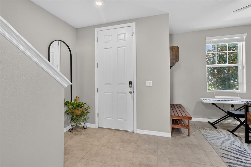 An entryway with tile flooring, a white front door, a staircase, and a wooden bench — 3310 WEITZEL DRIVE, HAINES CITY, FL