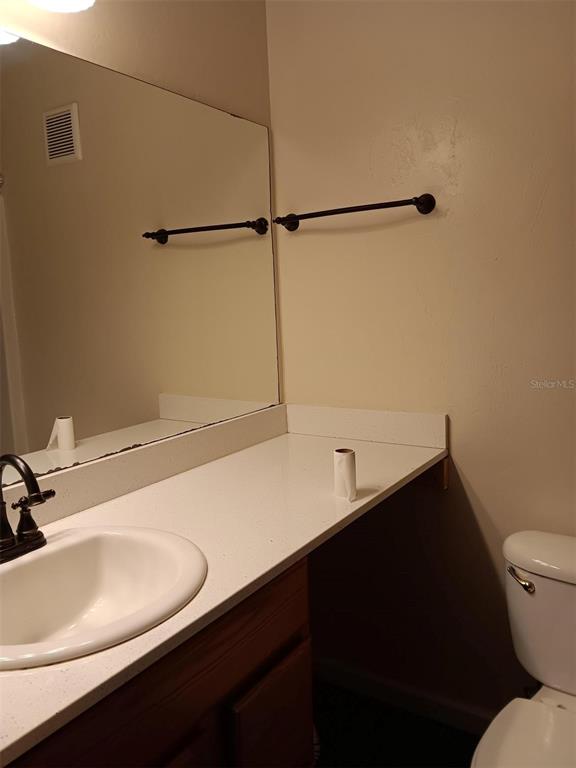 A bathroom vanity with a white countertop, sink, mirror, and a toilet to the right — 4000 SW 23RD STREET UNIT 4-308, GAINESVILLE, FL