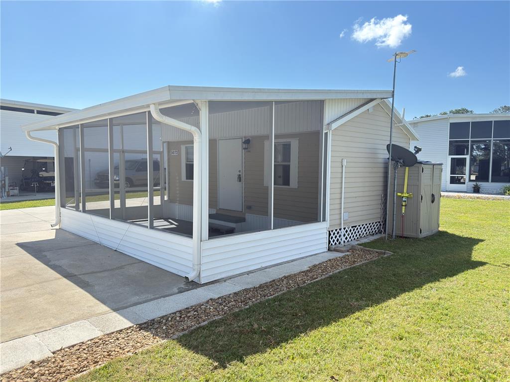A mobile home with a screened-in porch and beige siding sits on a grassy lot — 5073 SHORE LINE DRIVE, POLK CITY, FL