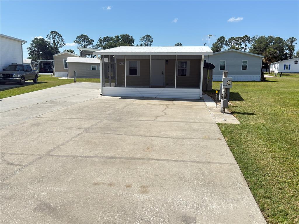 A mobile home with a screened-in front porch sits on a large concrete driveway — 5073 SHORE LINE DRIVE, POLK CITY, FL