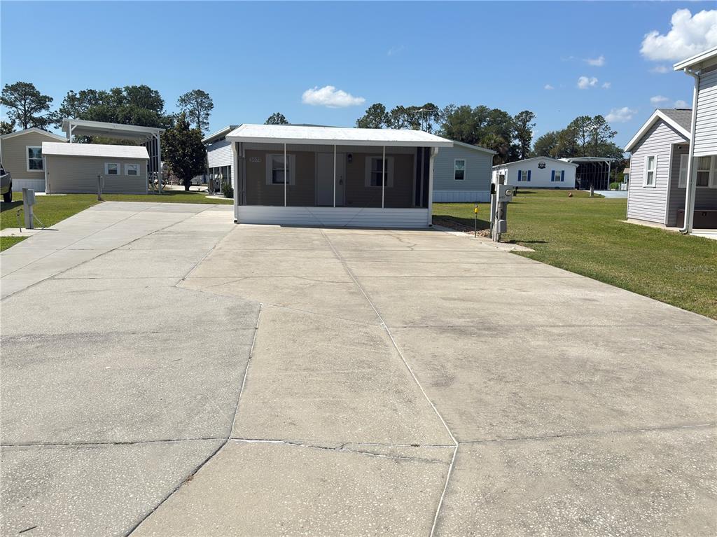 A mobile home with a large screened-in front porch sits behind a wide concrete driveway — 5073 SHORE LINE DRIVE, POLK CITY, FL