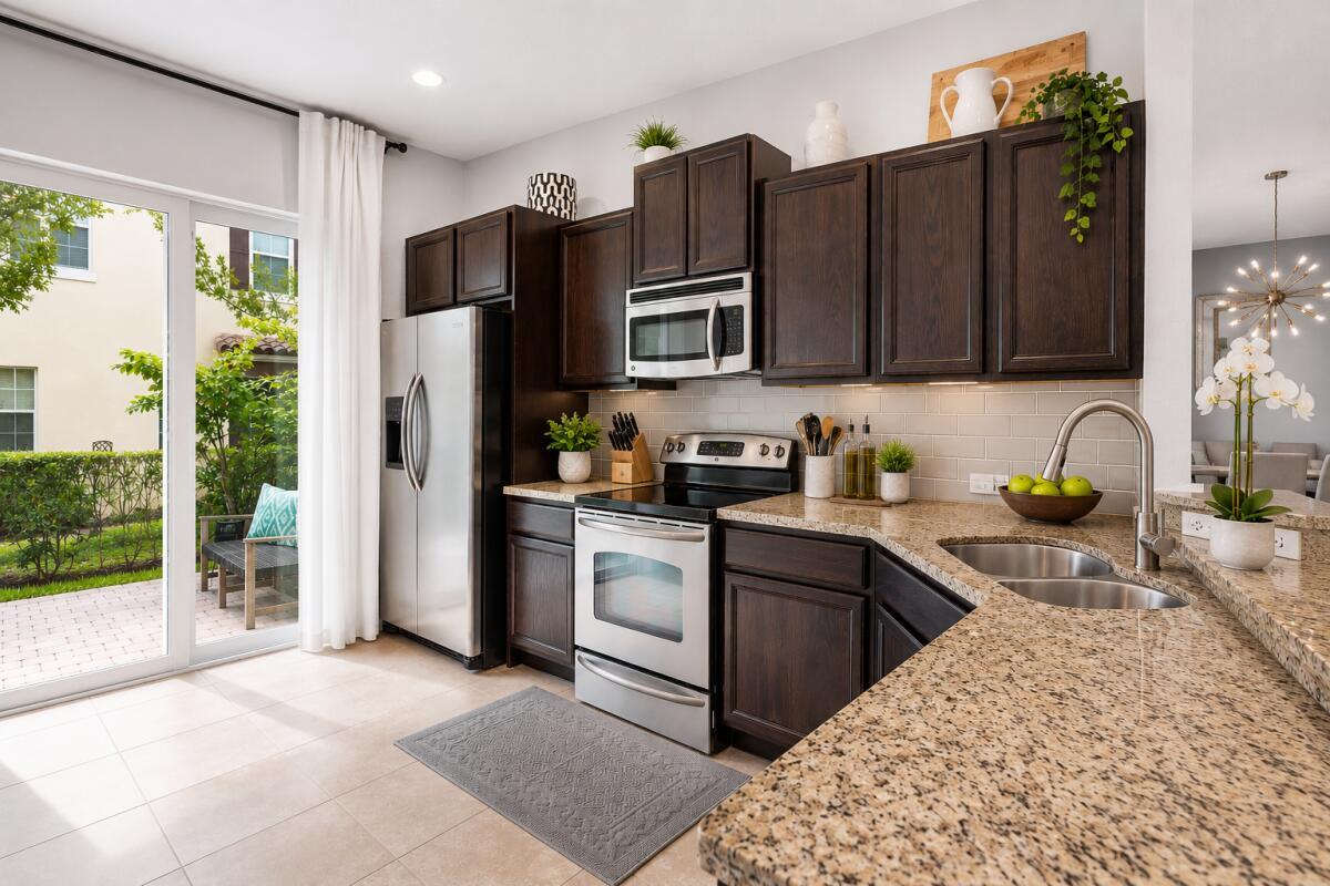 A kitchen features dark wood cabinets, granite countertops, stainless steel appliances, and a sliding glass door — 468 Francesca Ridge Road, Boynton Beach FL 33435, BOYNTON BEACH, FL