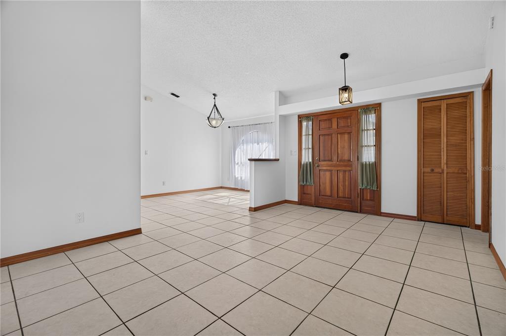 An entryway with beige tile flooring leads into a dining area with a vaulted ceiling — 4059 WATERVIEW LOOP, WINTER PARK, FL