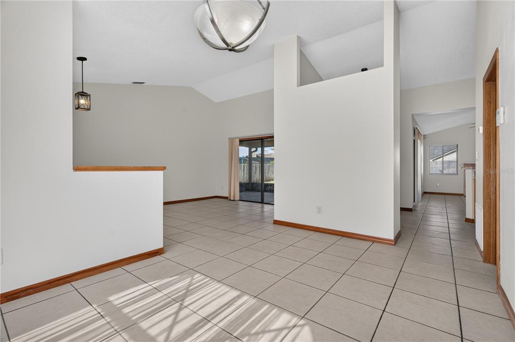 An open-concept living area features light-colored tile flooring, vaulted ceilings, and a sliding glass door — 4059 WATERVIEW LOOP, WINTER PARK, FL