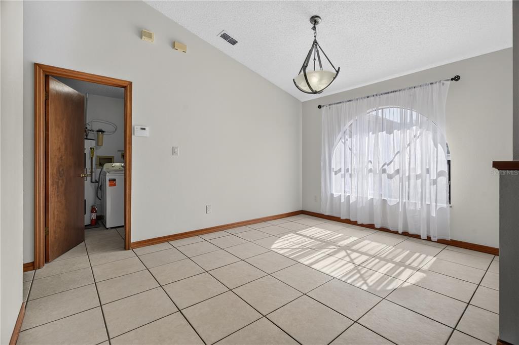 An empty dining room with tile floors, a vaulted ceiling, and a laundry room doorway — 4059 WATERVIEW LOOP, WINTER PARK, FL
