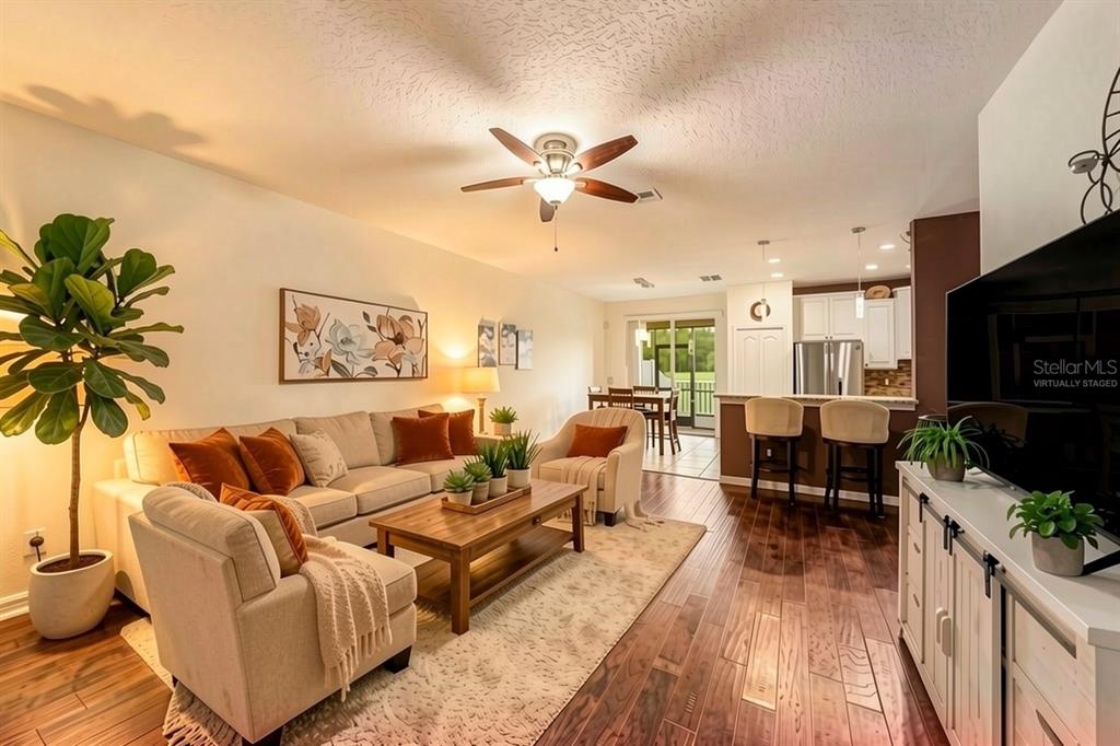 A living room with wood floors, a ceiling fan, and a kitchen with bar seating — 11927 GREENGATE DRIVE, HUDSON, FL