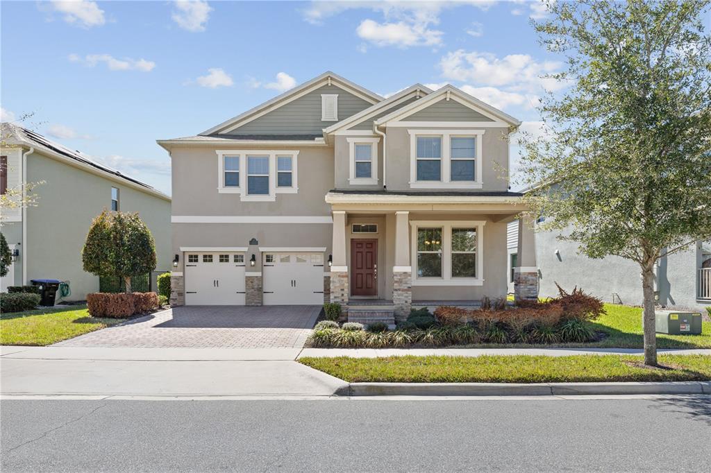A two-story suburban house with a two-car garage, stone accents, and a front porch — 15537 MANGO ISLE STREET, WINTER GARDEN, FL