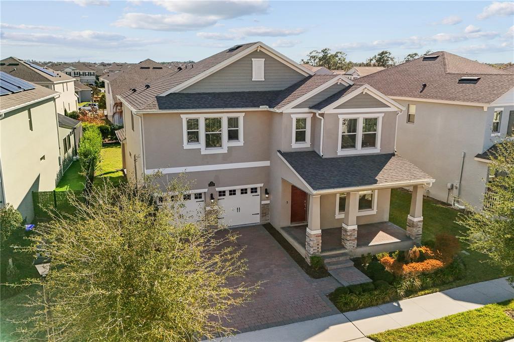 An aerial view of a two-story suburban house with a brick driveway and front porch — 15537 MANGO ISLE STREET, WINTER GARDEN, FL