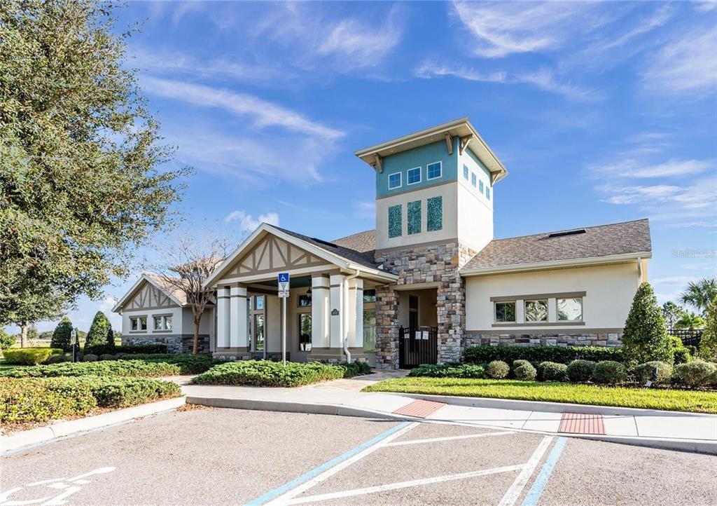 A beige and stone community clubhouse exterior features a central tower and a parking lot — 15537 MANGO ISLE STREET, WINTER GARDEN, FL