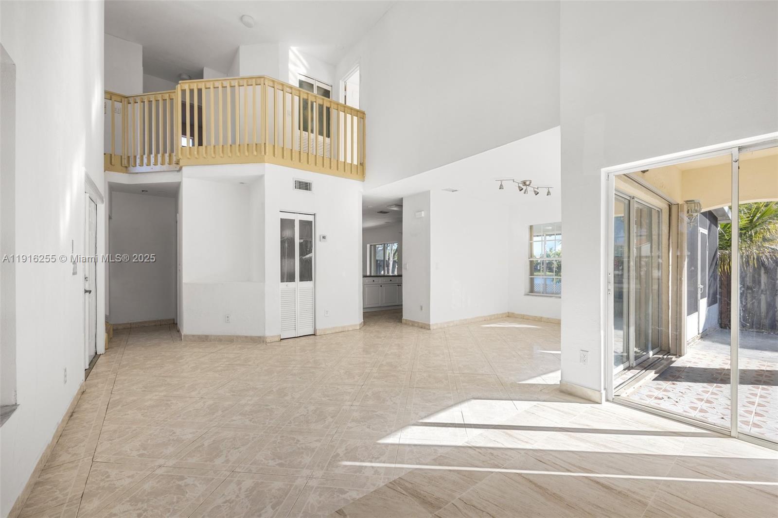 A bright, open-concept living area features high ceilings, tile flooring, and a wooden balcony loft — 9162 SW 213th Ln, Cutler Bay FL 33189, CUTLER BAY, FL
