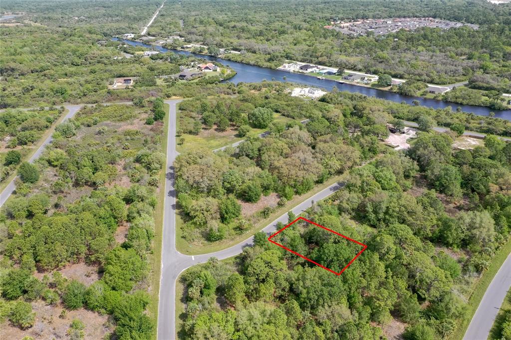 An aerial view shows a rectangular plot of land outlined in red amidst wooded terrain — 15047 DORN TERRACE, PORT CHARLOTTE, FL