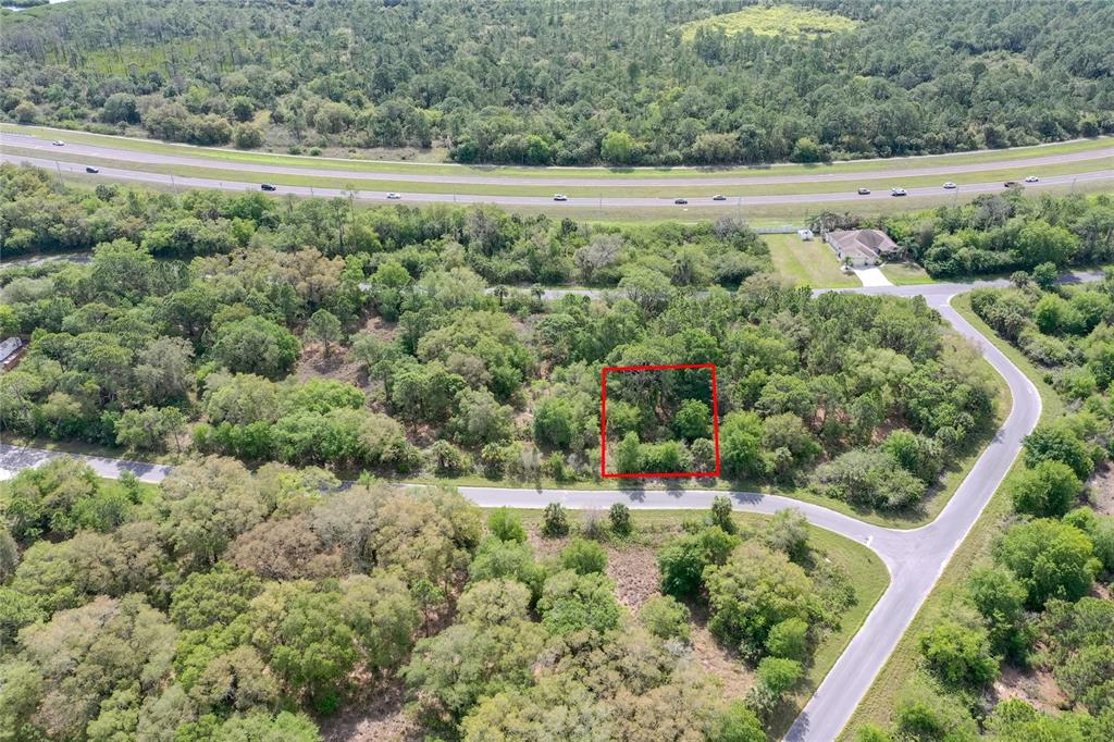 An aerial view shows a rectangular plot of land outlined in red amidst wooded surroundings — 15047 DORN TERRACE, PORT CHARLOTTE, FL