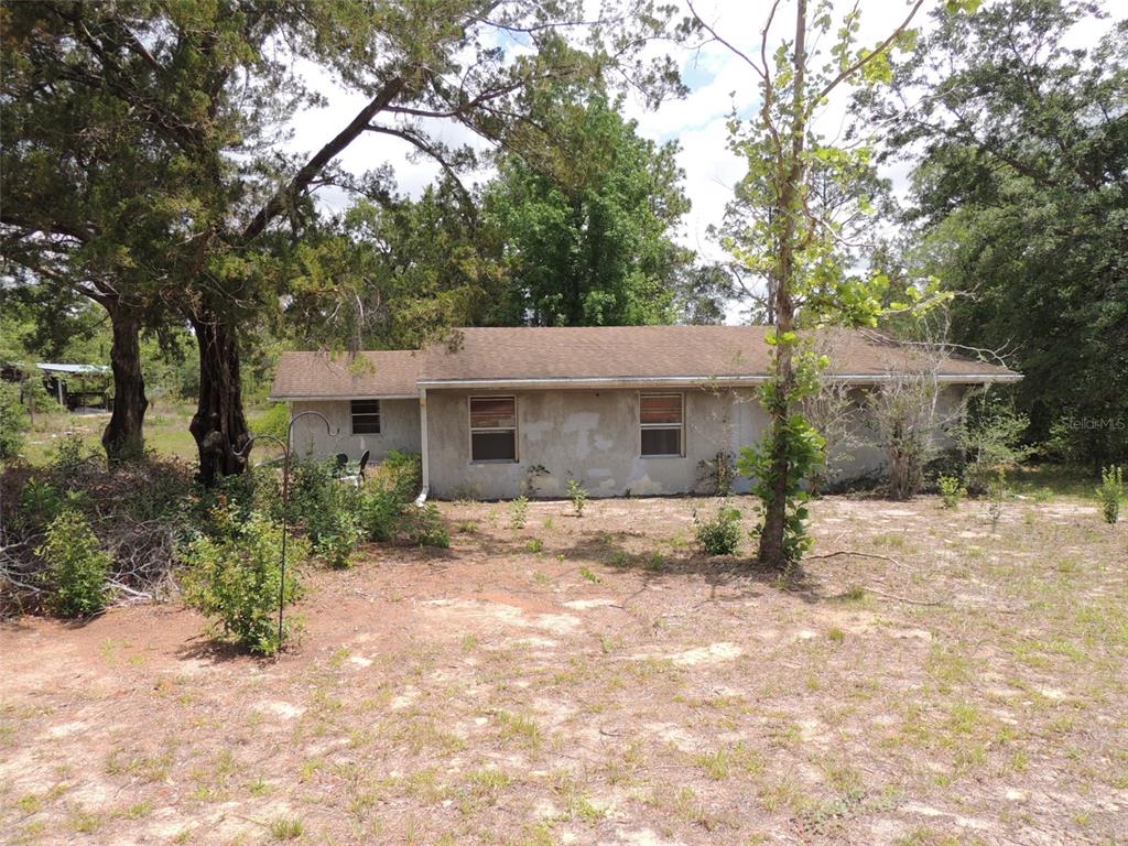 A single-story house with a stucco exterior sits on a sandy, partially wooded lot — 11351 SE 32ND PLACE, MORRISTON, FL