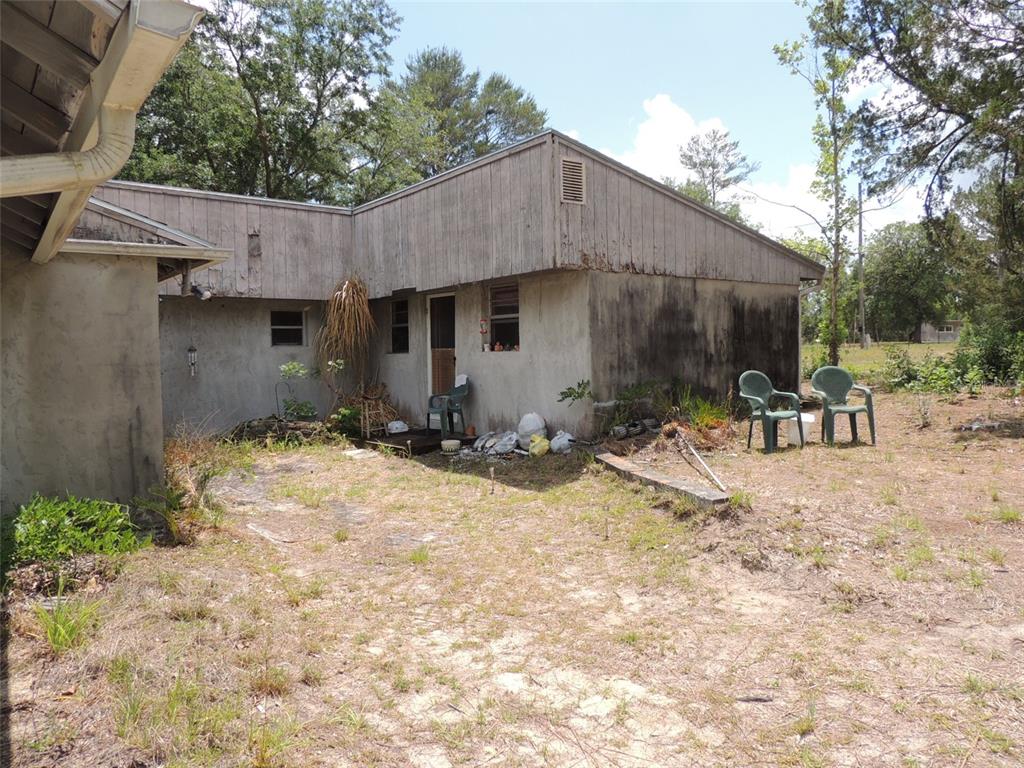 The exterior of a weathered, single-story house with stucco walls and wood siding — 11351 SE 32ND PLACE, MORRISTON, FL