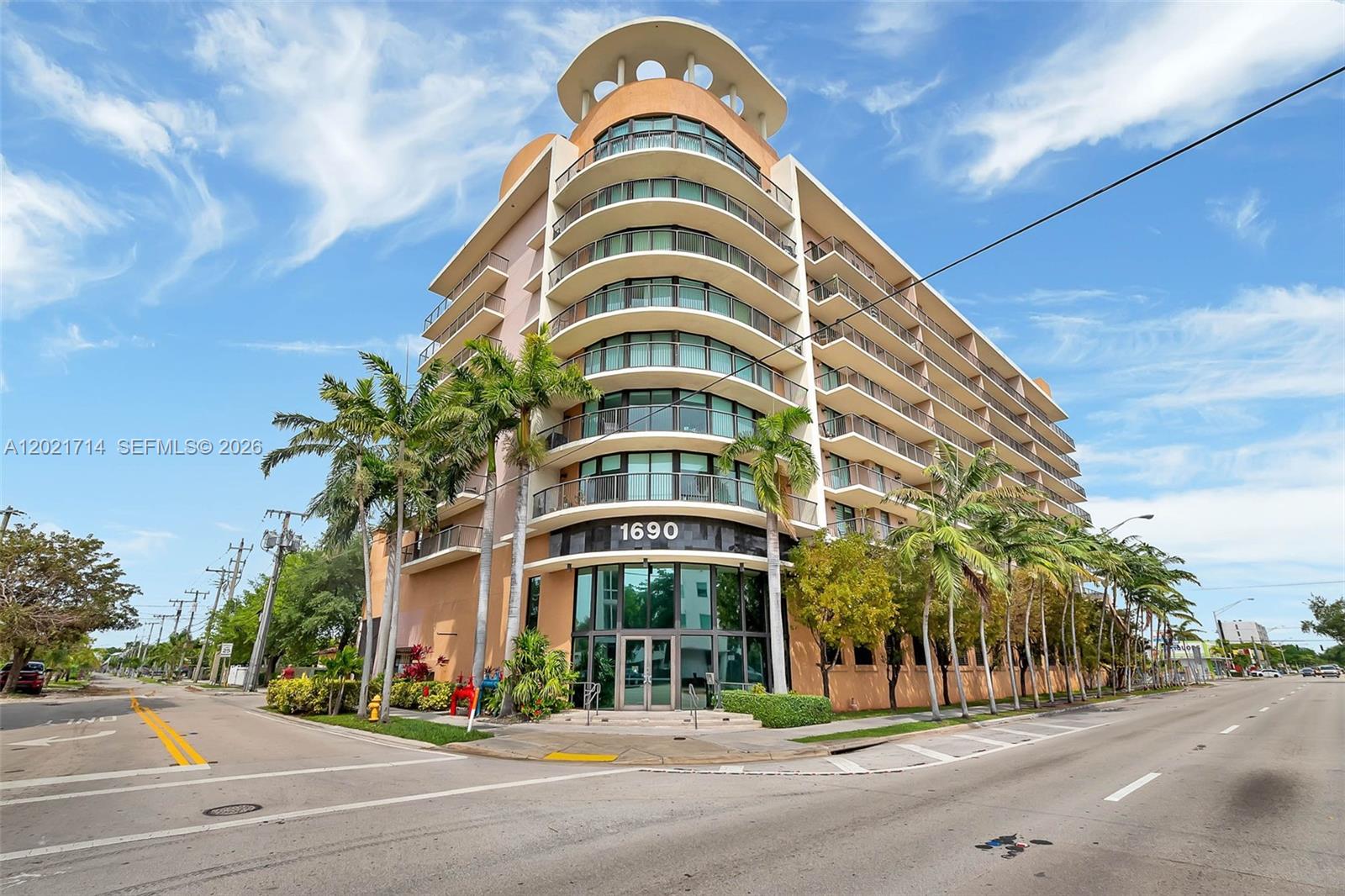 A multi-story residential building with curved balconies and a glass entrance stands on a corner — 1690 SW 27th Ave # 805, Miami FL 33145, MIAMI, FL