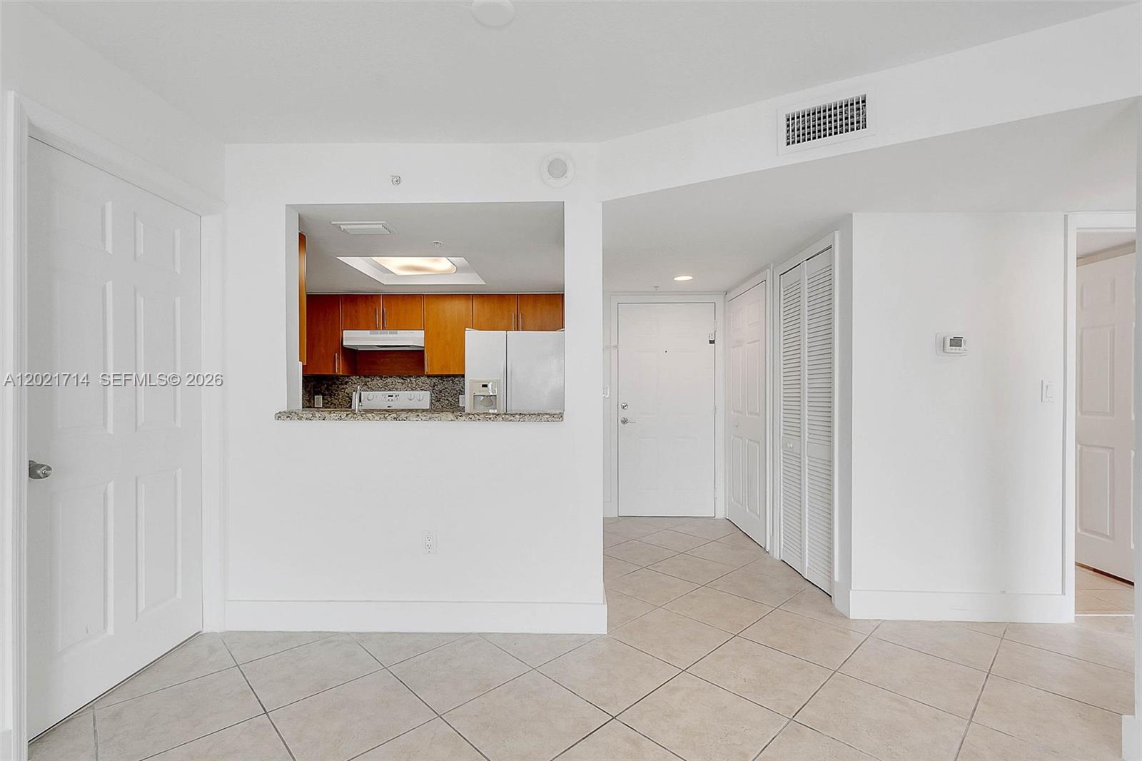 A tiled entryway leads to a kitchen with wood cabinets and a pass-through window — 1690 SW 27th Ave # 805, Miami FL 33145, MIAMI, FL