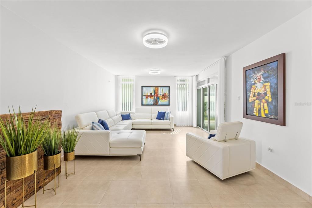 A bright living room features white leather sofas, tile flooring, and a large framed painting — JASPER ST. TREASURE POINT UNIT 50, VEGA ALTA, PR