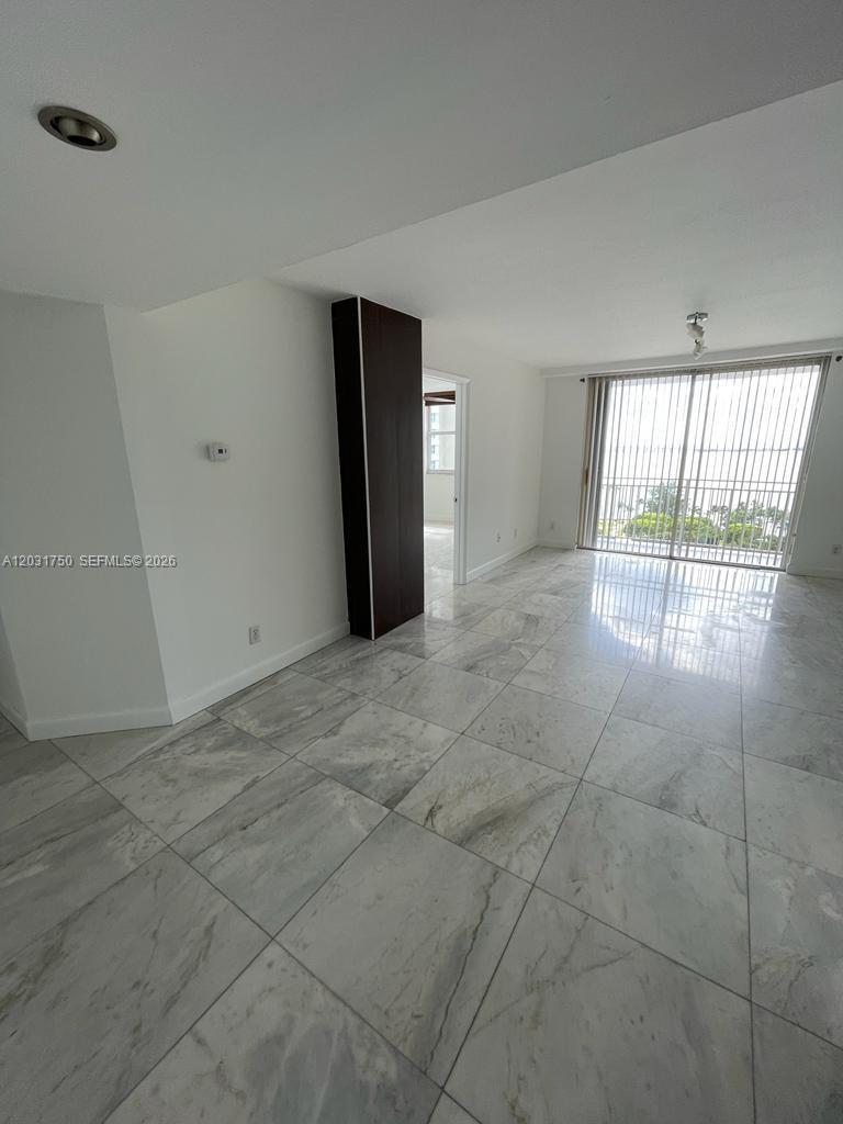 A bright living area features white walls, marble-style tile flooring, and a sliding glass door — 770 Claughton Island Dr # 1504, Miami FL 33131, MIAMI, FL