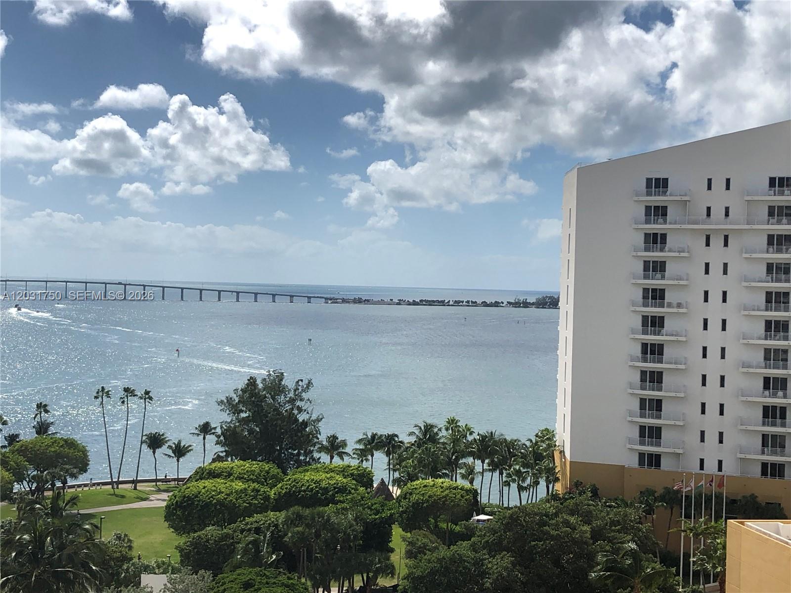 A high-rise building overlooks a bay with a long bridge under a cloudy sky — 770 Claughton Island Dr # 1504, Miami FL 33131, MIAMI, FL