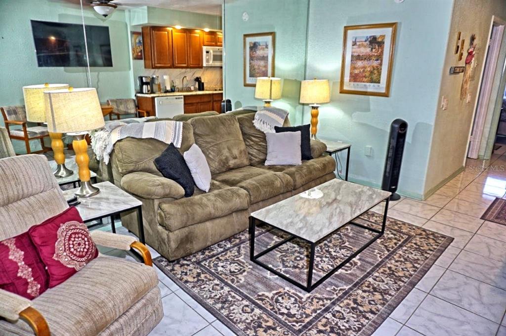 A living room features a brown sofa, a marble-topped coffee table, and an adjacent kitchen — 20921 HAULOVER COVE UNIT F5, LUTZ, FL