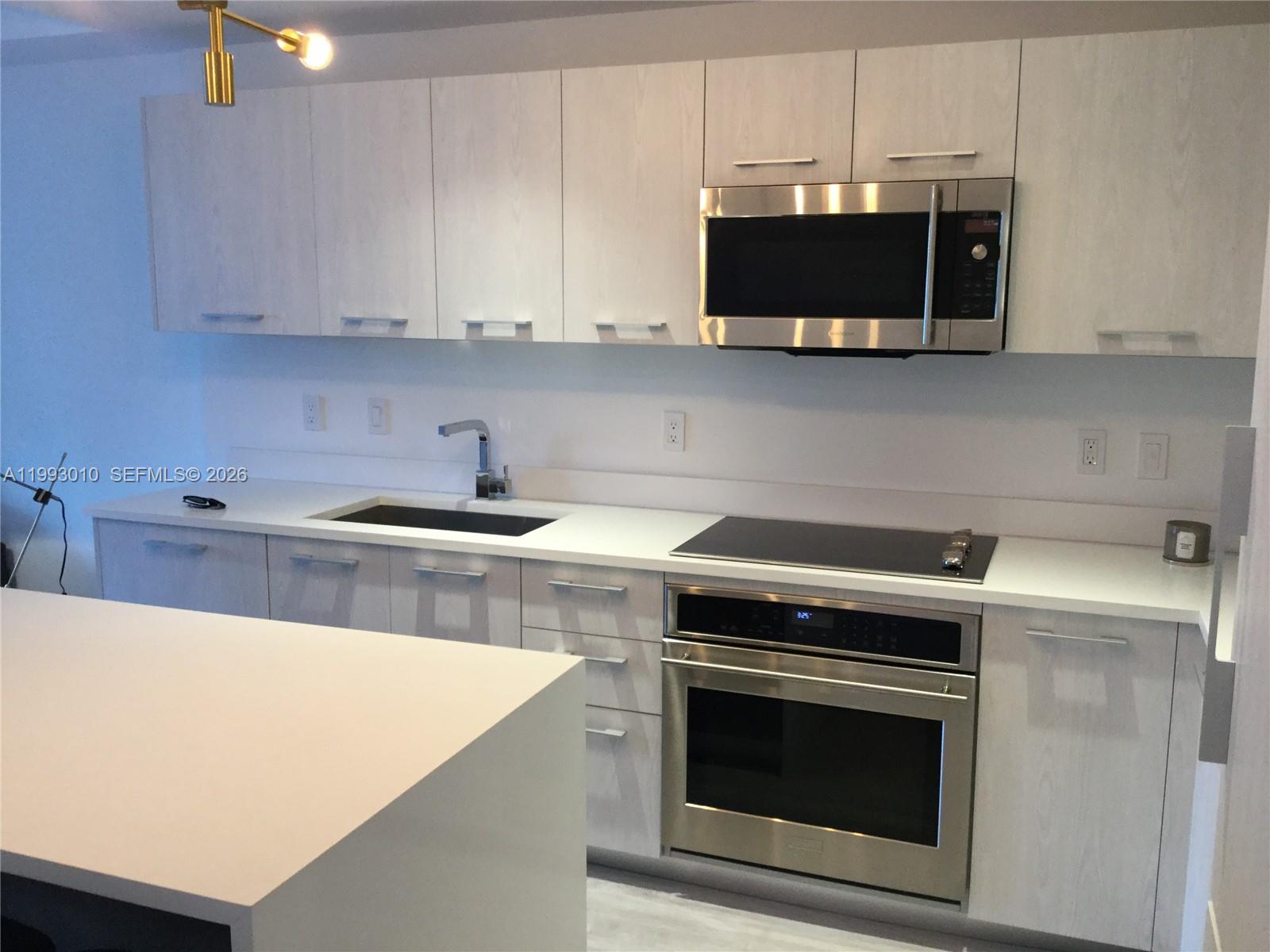 A modern kitchen features light wood cabinets, stainless steel appliances, and white quartz countertops — 55 SW 9th St # 1905, Miami FL 33130, MIAMI, FL