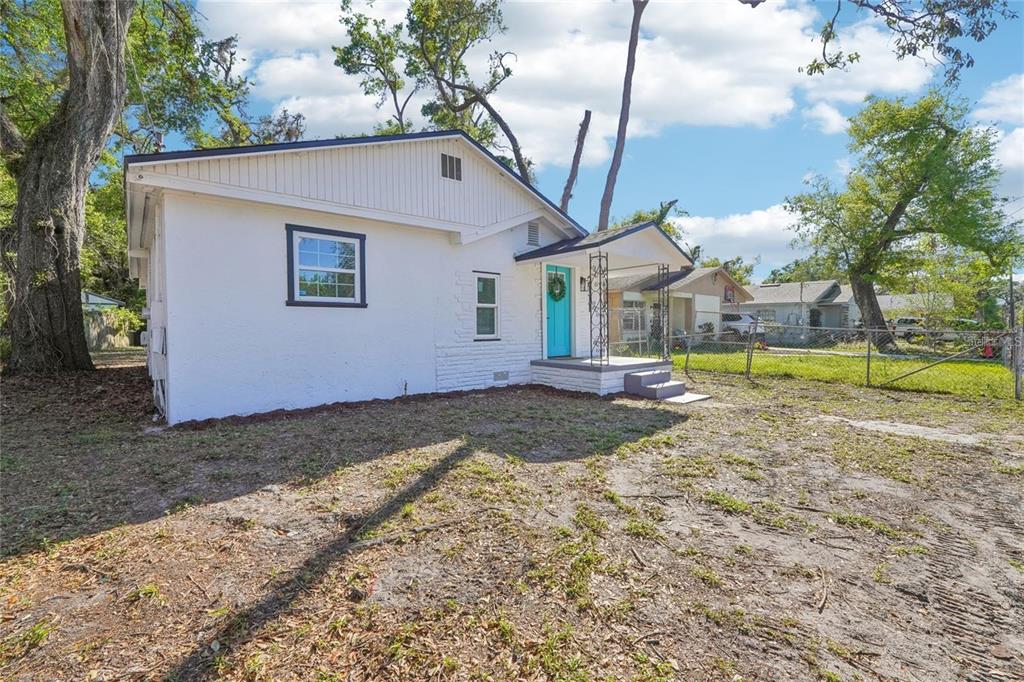 A white single-story house with a blue front door and a small covered porch — 2111 E ELLICOTT STREET, TAMPA, FL