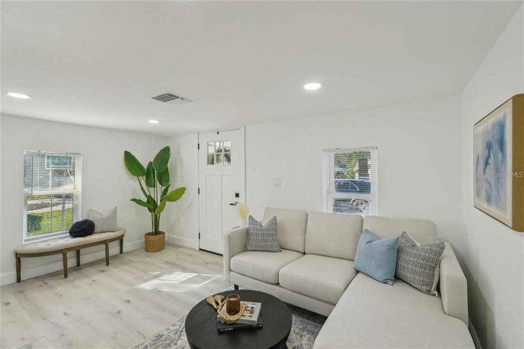 A bright living room features a white sectional sofa, a round coffee table, and a bench — 2111 E ELLICOTT STREET, TAMPA, FL