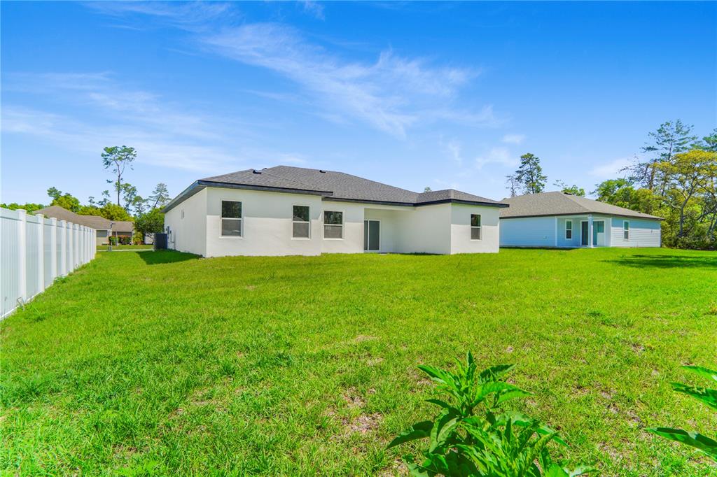 The back exterior of a white single-story house with a lawn and a vinyl fence — 3908 SW 171ST LANE, OCALA, FL