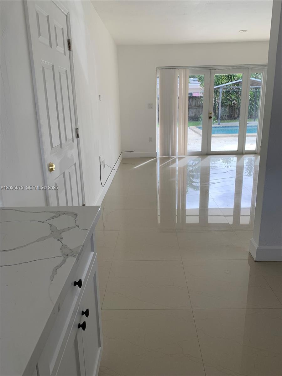 A bright room with light tile floors features a white cabinet and glass patio doors — 2025 SW 84th Ct, Miami FL 33155, MIAMI, FL