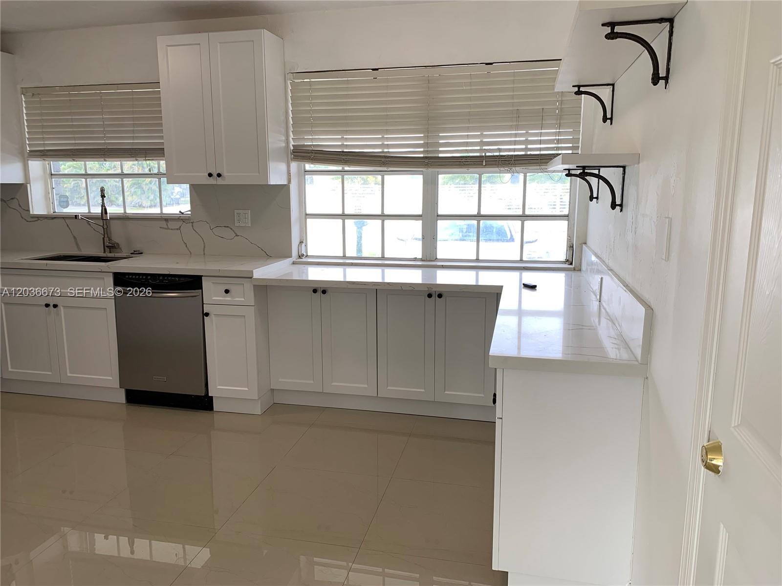 A kitchen features white cabinets, quartz countertops, stainless steel appliances, and large floor tiles — 2025 SW 84th Ct, Miami FL 33155, MIAMI, FL