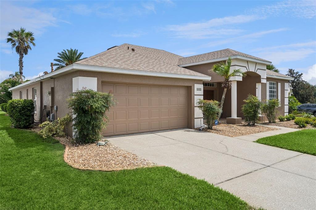 A single-story house with a tan stucco exterior, a two-car garage, and a covered entryway — 232 VIA MARIEL EAST DRIVE, DAVENPORT, FL