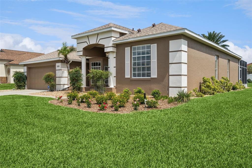 A single-story house with a brown stucco exterior, white trim, and a front garden — 232 VIA MARIEL EAST DRIVE, DAVENPORT, FL
