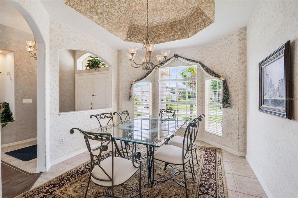 A dining room features a glass-top table, wrought iron chairs, and a tray ceiling — 232 VIA MARIEL EAST DRIVE, DAVENPORT, FL