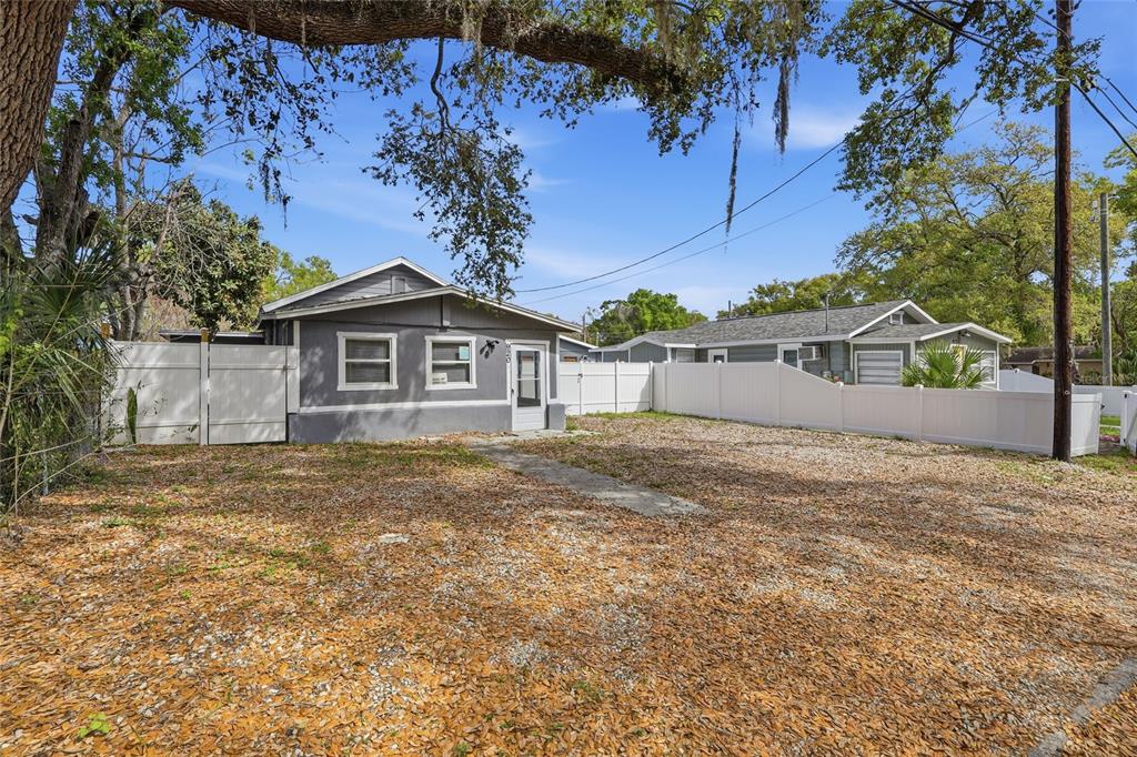 A gray house with a white fence stands on a gravel lot under trees — 920 E ANNIE STREET, TAMPA, FL
