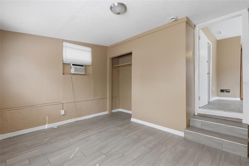 A room with light brown walls, gray wood-look flooring, a closet, and a window AC unit — 920 E ANNIE STREET, TAMPA, FL
