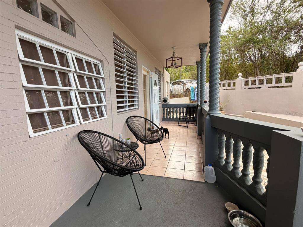 A covered porch features two black chairs, a tiled floor, and decorative columns — 101 ISIDORO CAMACHO, LAJAS, PR