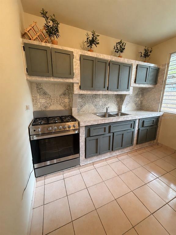 A kitchen features gray cabinets, a stainless steel gas range, and patterned tile backsplashes — 101 ISIDORO CAMACHO, LAJAS, PR