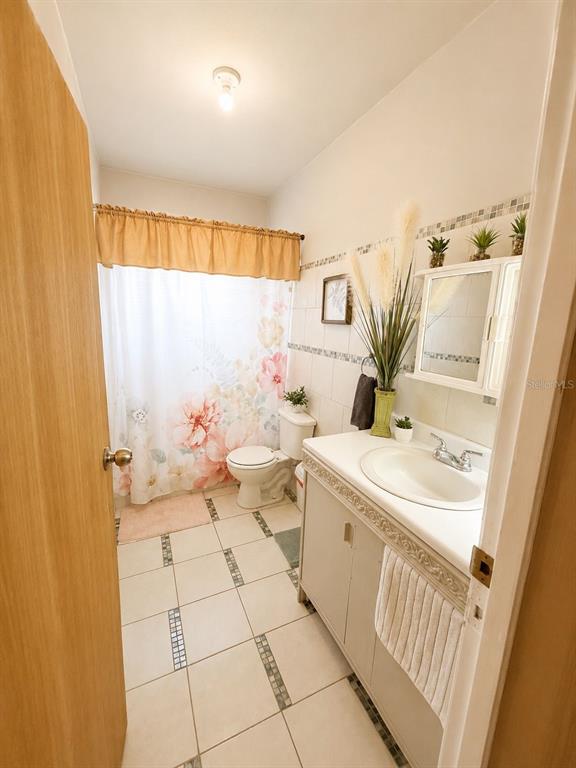 A bathroom features a floral shower curtain, a white toilet, and a vanity with sink — 101 ISIDORO CAMACHO, LAJAS, PR