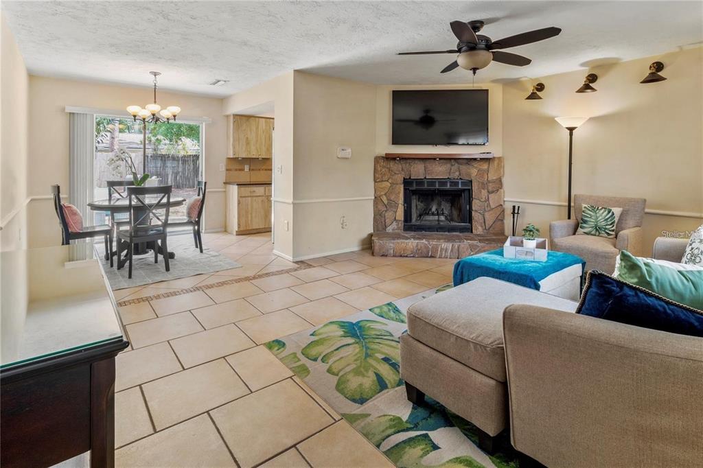 A living room with tile floors, a stone fireplace, and an adjacent dining area — 3314 ISLAND DATE CIRCLE, SARASOTA, FL
