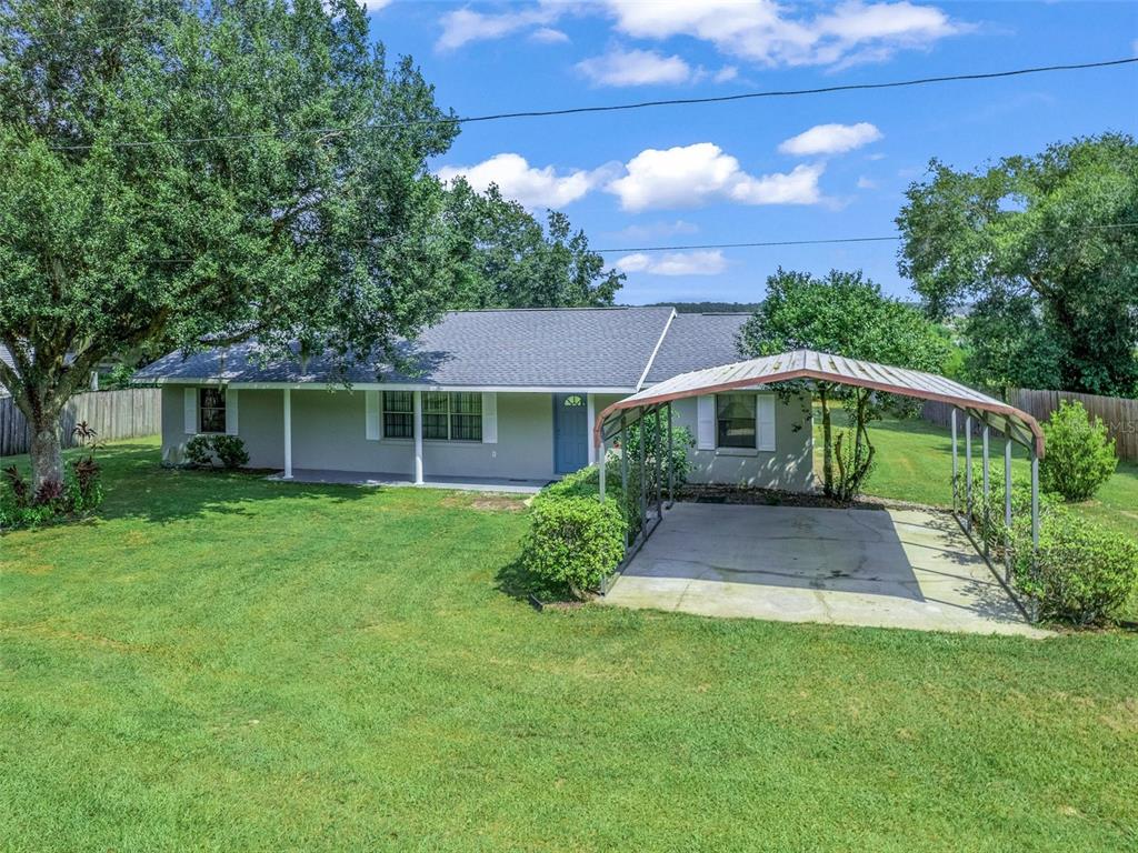 A single-story house with a gray roof, light siding, and a detached metal carport — 11495 SE 121ST LANE ROAD, BELLEVIEW, FL
