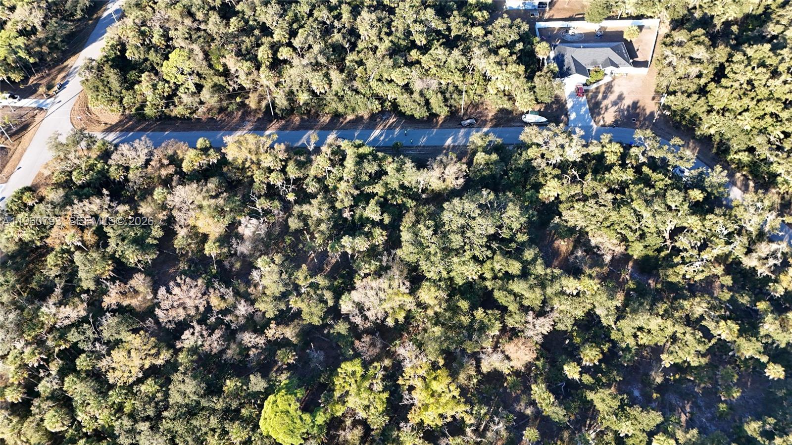 An aerial view shows a wooded lot bordered by a paved road and nearby houses — 0 BACKERT RD, North Port FL 34291, NORTH PORT, FL