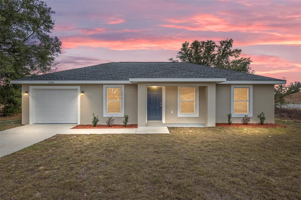 A single-story house with a beige stucco exterior, a blue front door, and a garage — 15393 SW 26TH PLACE, OCALA, FL