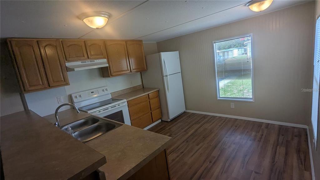 A kitchen features wood cabinets, a white stove, a refrigerator, and wood-look flooring — 39518 STERLING DRIVE, ZEPHYRHILLS, FL