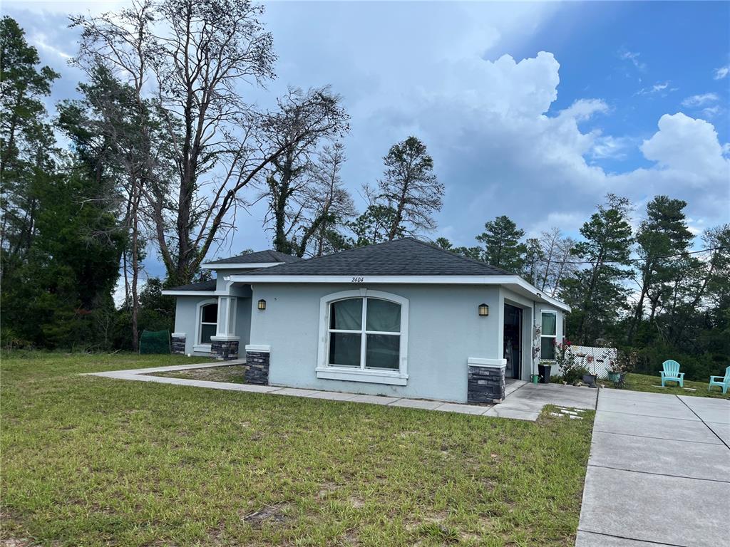 A single-story light blue house with a dark shingled roof and stone accents — 2404 LEMA DRIVE, SPRING HILL, FL