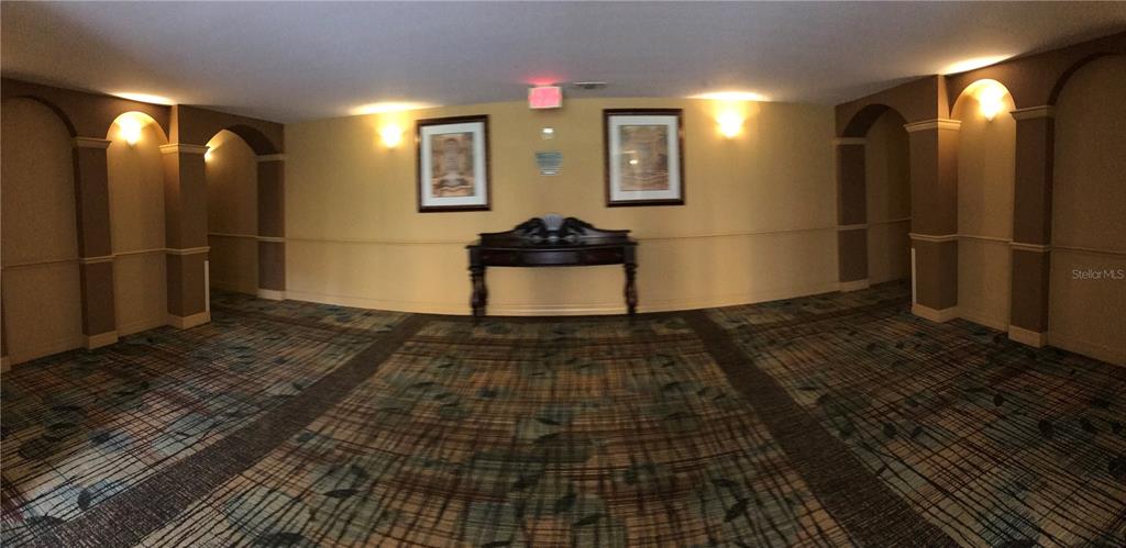 A carpeted hallway features a dark wooden console table between two framed pictures on walls — 8112 POINCIANA BOULEVARD UNIT 1302, ORLANDO, FL