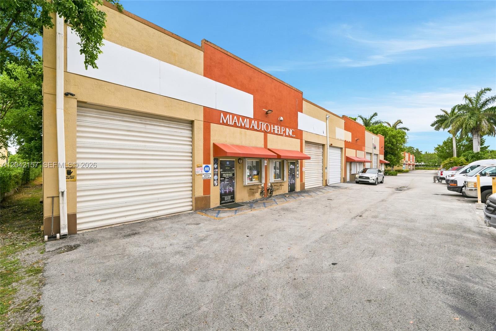 The exterior of a commercial warehouse building features roll-up doors and a small office entrance — 11951 SW 144th Ct, Miami FL 33186, MIAMI, FL
