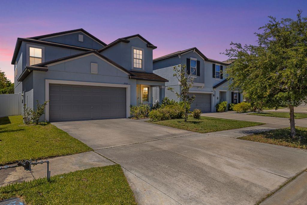 A two-story suburban house with a two-car garage and a concrete driveway at dusk — 3703 GLOBE THISTLE DRIVE, TAMPA, FL
