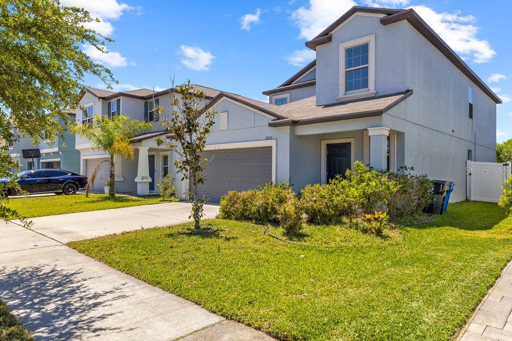 A two-story suburban house with a gray stucco exterior, a two-car garage, and a lawn — 3703 GLOBE THISTLE DRIVE, TAMPA, FL
